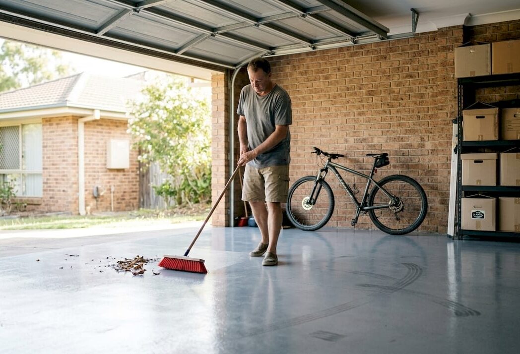 Homeowner sweeping clean epoxy garage floor