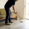 Worker applying sealer to living room floor