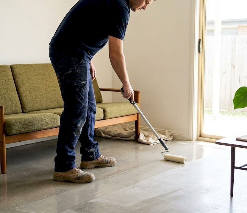 Worker applying sealer to living room floor